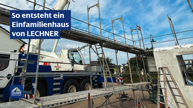 Ein Rohbau eines Einfamilienhauses von LECHNER Massivhaus, umgeben von einem Gerüst und einem blauen Baukran mit der Aufschrift 'LIEBHERR' und 'Erdbau & Philipp'. Die Szene spielt unter einem leicht bewölkten blauen Himmel.