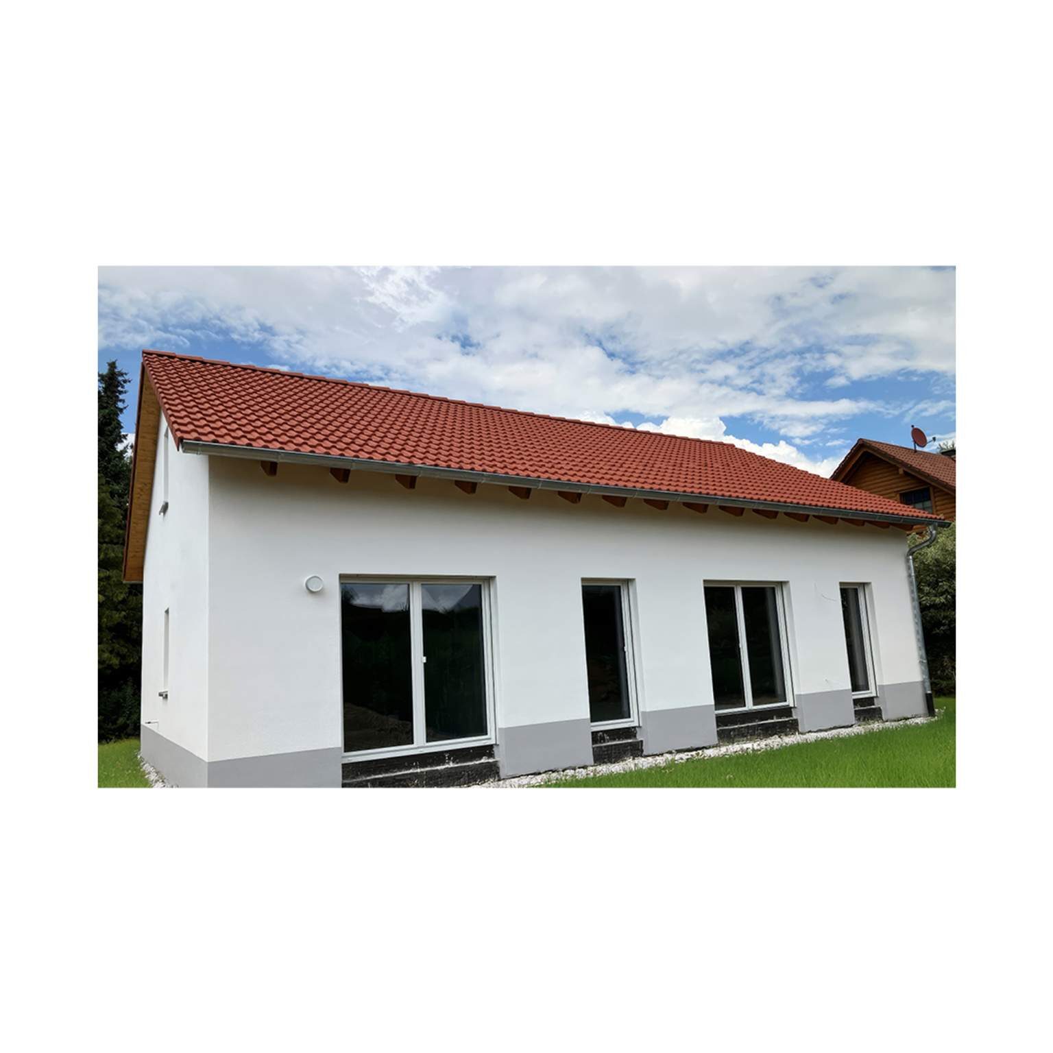 Klassisches Einfamilienhaus mit rotem Ziegeldach und bodentiefen Terrassentüren.