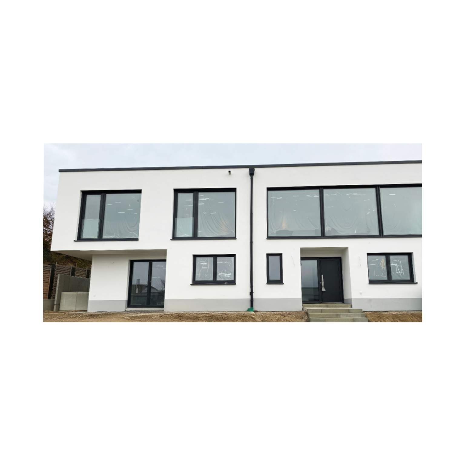 Puristisches Mehrfamilienhaus mit Flachdach und großzügigen Fensterfronten in Massivbauweise.