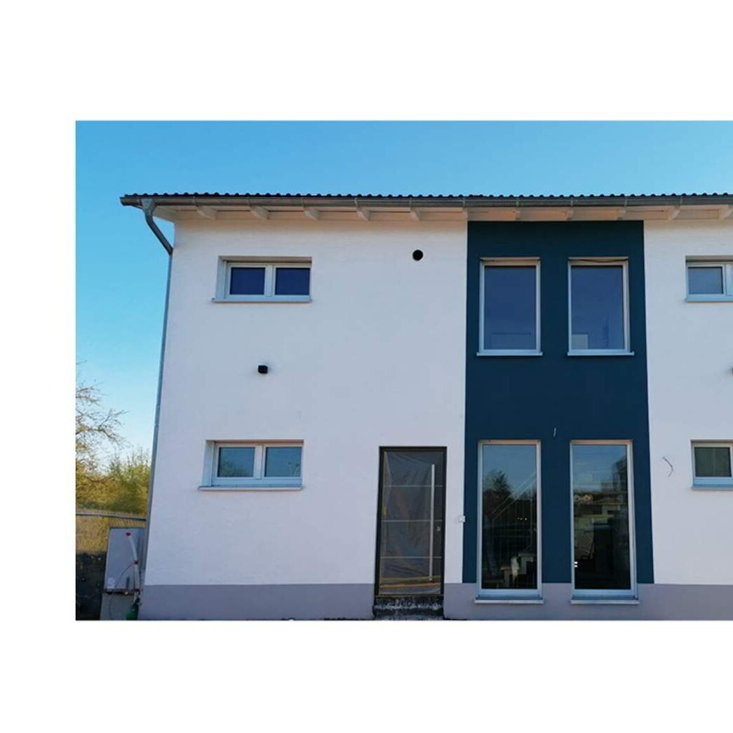 Modernes Doppelhaus in Massivbauweise mit kontrastierender blauer Fassadengestaltung und bodentiefen Fenstern von Lechner Massivhaus.