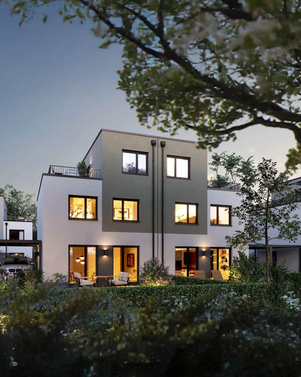 Kubisches, dreistöckiges Stadthaus, dunkle/weiße Fassade, beleuchtet bei Dämmerung, minimalistisches Design.