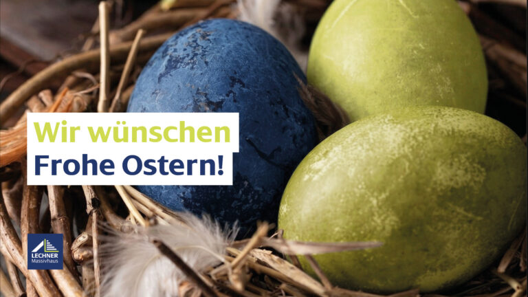 Ostergrüße von Lechner Massivhaus: Detailaufnahme eines Osternests aus Naturzweigen mit einem dunkelblauen und zwei hellgrünen Ostereiern sowie weißen Federn. Text-Overlay: Wir wünschen Frohe Ostern!