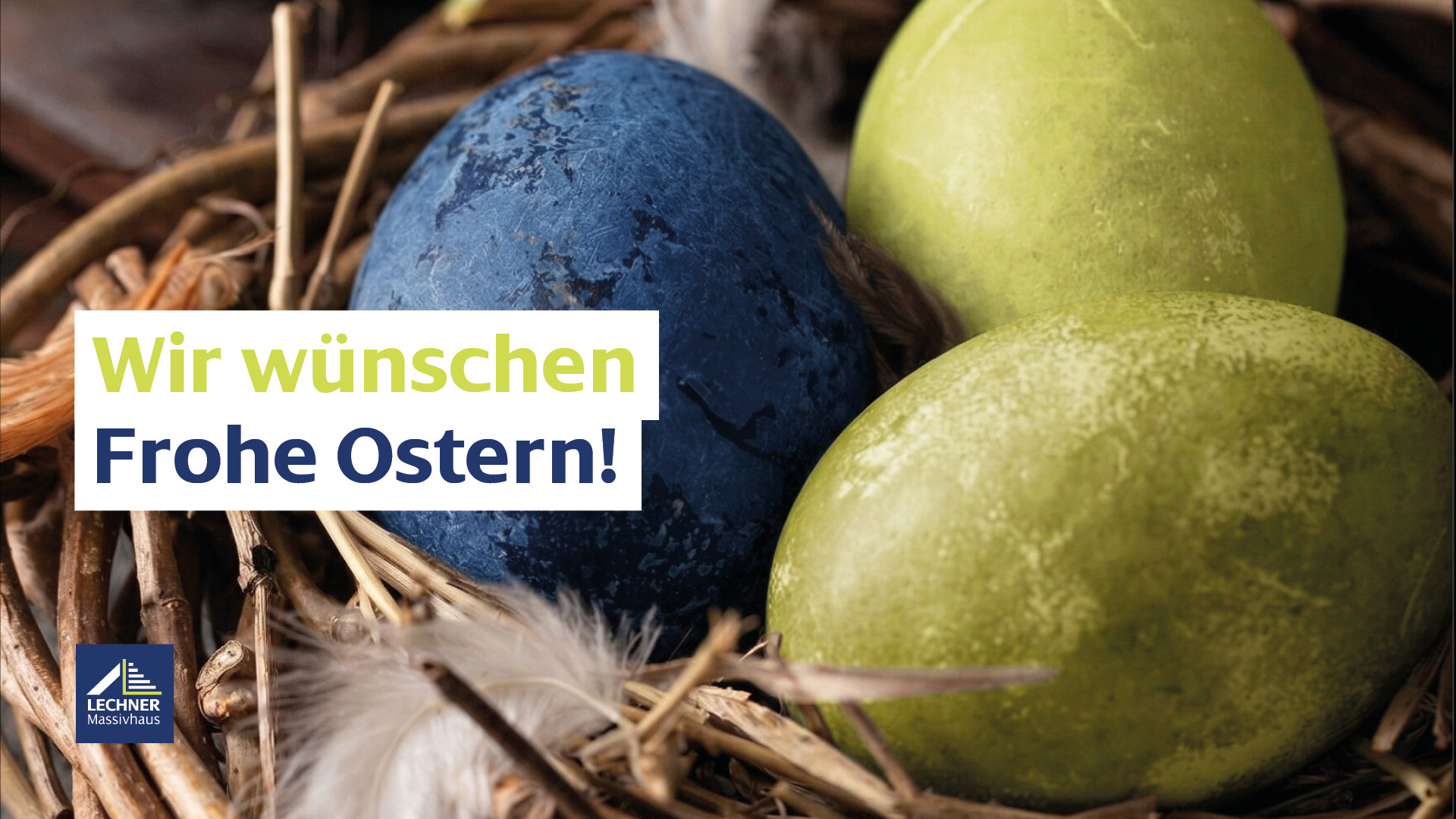 Ostergrüße von Lechner Massivhaus: Detailaufnahme eines Osternests aus Naturzweigen mit einem dunkelblauen und zwei hellgrünen Ostereiern sowie weißen Federn. Text-Overlay: Wir wünschen Frohe Ostern!
